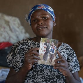 Joyce uit Zimbabwe kijkt verdrietig en houdt een foto vast waarop ze met haar dochter in haar armen te zien is