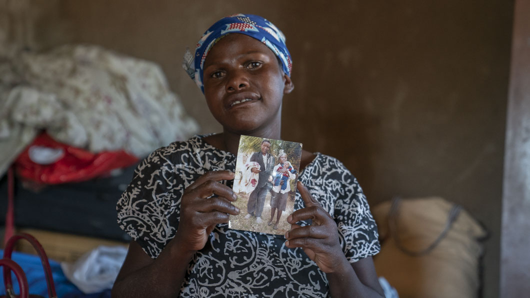 Joyce uit Zimbabwe kijkt verdrietig en houdt een foto vast waarop ze met haar dochter in haar armen te zien is